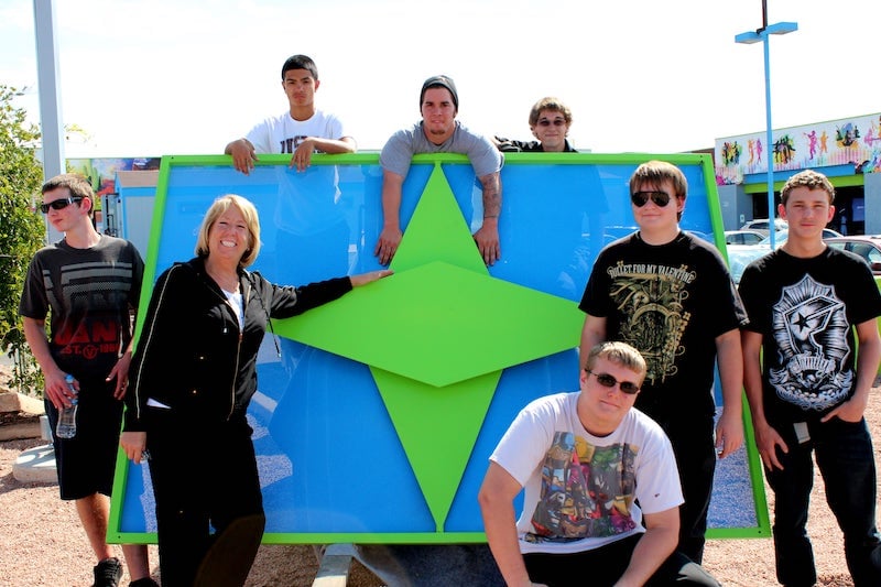 Compass High School founder Debbie Ferguson and students in front of the new Compass High School sign